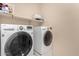 Bright laundry room featuring a modern washer and dryer with convenient shelving at 3687 E Blue Spruce Ln, Gilbert, AZ 85298