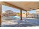 Covered backyard patio area with a view of the pool and desert landscaping at 42015 W Hillman Dr, Maricopa, AZ 85138
