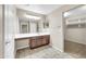 Bright bathroom featuring a long vanity with dark cabinets and a doorway leading to another room at 42015 W Hillman Dr, Maricopa, AZ 85138
