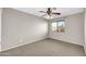 A simple bedroom features neutral walls, carpet, a large window, and a ceiling fan with a light at 42015 W Hillman Dr, Maricopa, AZ 85138