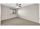 A simple bedroom features neutral walls, carpet, a large window, and a ceiling fan at 42015 W Hillman Dr, Maricopa, AZ 85138