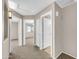 Hallway view leading to two bedrooms, one with an ensuite bathroom with carpeted floors at 42015 W Hillman Dr, Maricopa, AZ 85138
