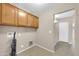 Well-organized laundry room with overhead cabinets and access to another room at 42015 W Hillman Dr, Maricopa, AZ 85138