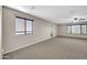 An expansive main bedroom with neutral walls and carpet has abundant natural light from two windows at 42015 W Hillman Dr, Maricopa, AZ 85138