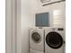 Well-organized laundry room featuring front loading washer and dryer with blue cabinets and natural light at 42943 N Livingstone Way, Anthem, AZ 85086