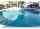 This outdoor pool is surrounded by palm trees, umbrellas and lounge chairs with neighborhood buildings in the background at 5124 N 31St Pl # 536, Phoenix, AZ 85016