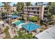 Aerial view of a community pool with covered seating areas, palm trees, and nearby condo buildings at 5124 N 31St Pl # 536, Phoenix, AZ 85016