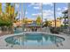 This outdoor pool is equipped with palm trees, lounge chairs, and umbrellas with neighborhood buildings in the background at 5124 N 31St Pl # 536, Phoenix, AZ 85016