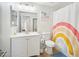 Bright bathroom featuring a white vanity, framed mirror, toilet and a rainbow-themed shower curtain at 6123 W Karen Lee Ln, Glendale, AZ 85306