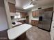 Traditional kitchen with wooden cabinets, white countertops, stainless steel refrigerator and a tiled floor at 6132 E Decatur St, Mesa, AZ 85205