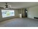 Cozy living room with neutral carpet, a large window overlooking the front yard, and built-in shelving at 6132 E Decatur St, Mesa, AZ 85205