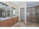 Bathroom featuring a double vanity, large mirror, and glass shower at 7420 W Los Gatos Dr, Glendale, AZ 85310