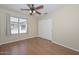 Well-lit bedroom with wood-look floors, a ceiling fan, and sliding closet doors at 7420 W Los Gatos Dr, Glendale, AZ 85310