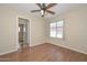 Serene bedroom with wood-look flooring, a ceiling fan, and a window with views at 7420 W Los Gatos Dr, Glendale, AZ 85310