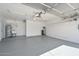 Garage showcasing epoxy floors, utility sink, water heater, ceiling fan, and white shelving at 7420 W Los Gatos Dr, Glendale, AZ 85310