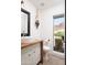 Chic powder room featuring sleek fixtures, a decorative mirror, and a view of the outdoors at 7508 N 21St St, Phoenix, AZ 85020