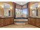 Bright bathroom with double vanities, a soaking tub overlooking outdoor scenery, and neutral tile at 10224 N Azure Vista Trl, Fountain Hills, AZ 85268