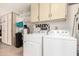 A well-stocked laundry room, including laundry machines, a sink, and shelving at 10511 W Wheatridge Dr, Sun City, AZ 85373