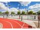 Well-maintained red running track next to fenced recreation area under a bright, cloudy sky at 10511 W Wheatridge Dr, Sun City, AZ 85373