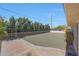 Backyard features gravel, a fence, mature trees, and a blue sky at 10650 W Riviera Dr, Sun City, AZ 85351