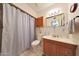 Standard bathroom with a shower curtain, wood cabinet, and neutral-toned fixtures at 10650 W Riviera Dr, Sun City, AZ 85351