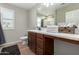 Bathroom featuring a wooden vanity, dual sinks, and a wall mirror, offering a functional and stylish space at 10983 W Mckinley St, Avondale, AZ 85323