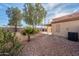 A cozy backyard with gravel landscaping, mature trees, and a covered patio area for outdoor enjoyment at 11955 W Granada Rd, Avondale, AZ 85392