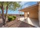 A peaceful backyard featuring gravel, lush shrubs, a mature shade tree, and a charming covered patio at 11955 W Granada Rd, Avondale, AZ 85392