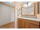 Bathroom featuring a wood vanity with granite counters, framed mirror, and decorative wall paper at 11955 W Granada Rd, Avondale, AZ 85392