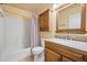 Bathroom with wood cabinets, granite countertop, framed mirror, and tub shower combo at 11955 W Granada Rd, Avondale, AZ 85392