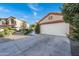 View of the front yard, desert landscaping, and the attached two car garage of the single-story home at 11955 W Granada Rd, Avondale, AZ 85392