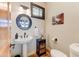 Stylish half-bathroom with pedestal sink, round mirror, and decorative accents at 13502 E Jomax Rd, Scottsdale, AZ 85262