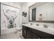 Stylish bathroom featuring a double sink vanity and modern fixtures, along with a decorative shower curtain at 14296 W Surrey Dr, Surprise, AZ 85379