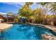 Backyard swimming pool featuring lush landscaping, shade, and a rock feature at 1541 E Hope St, Mesa, AZ 85203