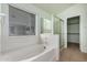 Bright bathroom featuring a soaking tub, a glass-enclosed shower, and a large window at 15601 W Hammond Dr, Goodyear, AZ 85338