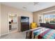 Bedroom featuring a dresser with a TV, a cheerful yellow chair, and a glimpse into the ensuite bathroom at 16200 W Hearthstone Dr, Surprise, AZ 85374