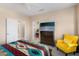 View of the bedroom with two doorways, a dresser with a TV, and a cozy yellow chair at 16200 W Hearthstone Dr, Surprise, AZ 85374