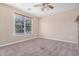 Bright bedroom featuring a large window, ceiling fan, and plush carpet flooring at 17192 W Post Dr, Surprise, AZ 85388