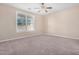 Bedroom features a large window, ceiling fan, and neutral carpet at 17192 W Post Dr, Surprise, AZ 85388