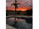 Tranquil pool at dusk reflecting a vibrant sunset and silhouetted palm trees, offering a serene retreat at 1831 W San Angelo St, Gilbert, AZ 85233