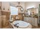 Bathroom showcasing a bathtub, decorative travertine tile, a granite vanity, and decorative light fixtures at 23415 S 202Nd St, Queen Creek, AZ 85142