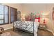 A bedroom featuring a decorative iron bed frame, colorful pillows, and window shutters for a cozy and inviting space at 23415 S 202Nd St, Queen Creek, AZ 85142