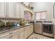 Bright laundry room with ample cabinetry, counter space, a sink, and modern washer and dryer units at 23415 S 202Nd St, Queen Creek, AZ 85142