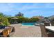 An outdoor pool area with a waterfall feature, lush landscaping, comfortable patio furniture, and well-maintained brick pavers at 23415 S 202Nd St, Queen Creek, AZ 85142