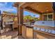 Outdoor kitchen with built-in grill, counter, stainless steel refrigerator, and dining area under string lights at 2463 E Stacey Rd, Gilbert, AZ 85298