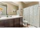 Bathroom with a single sink vanity featuring a large mirror and a toilet with a shower curtain at 25907 N 134Th Dr, Peoria, AZ 85383