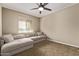 Comfortable bedroom featuring neutral carpet, a large window, ceiling fan, and a plush sectional sofa at 25907 N 134Th Dr, Peoria, AZ 85383