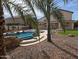 Beautiful backyard oasis featuring a swimming pool, rock features, and mature palm trees at 31487 N Blackfoot Dr, San Tan Valley, AZ 85143