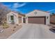 Inviting home showcases desert landscaping, a secure gate, and a brown two-car garage, under a sunny blue sky at 336 N Monterey Ct, Casa Grande, AZ 85194