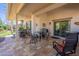 Inviting covered patio with tiled flooring, multiple seating areas, and a view of the lush backyard at 336 N Monterey Ct, Casa Grande, AZ 85194